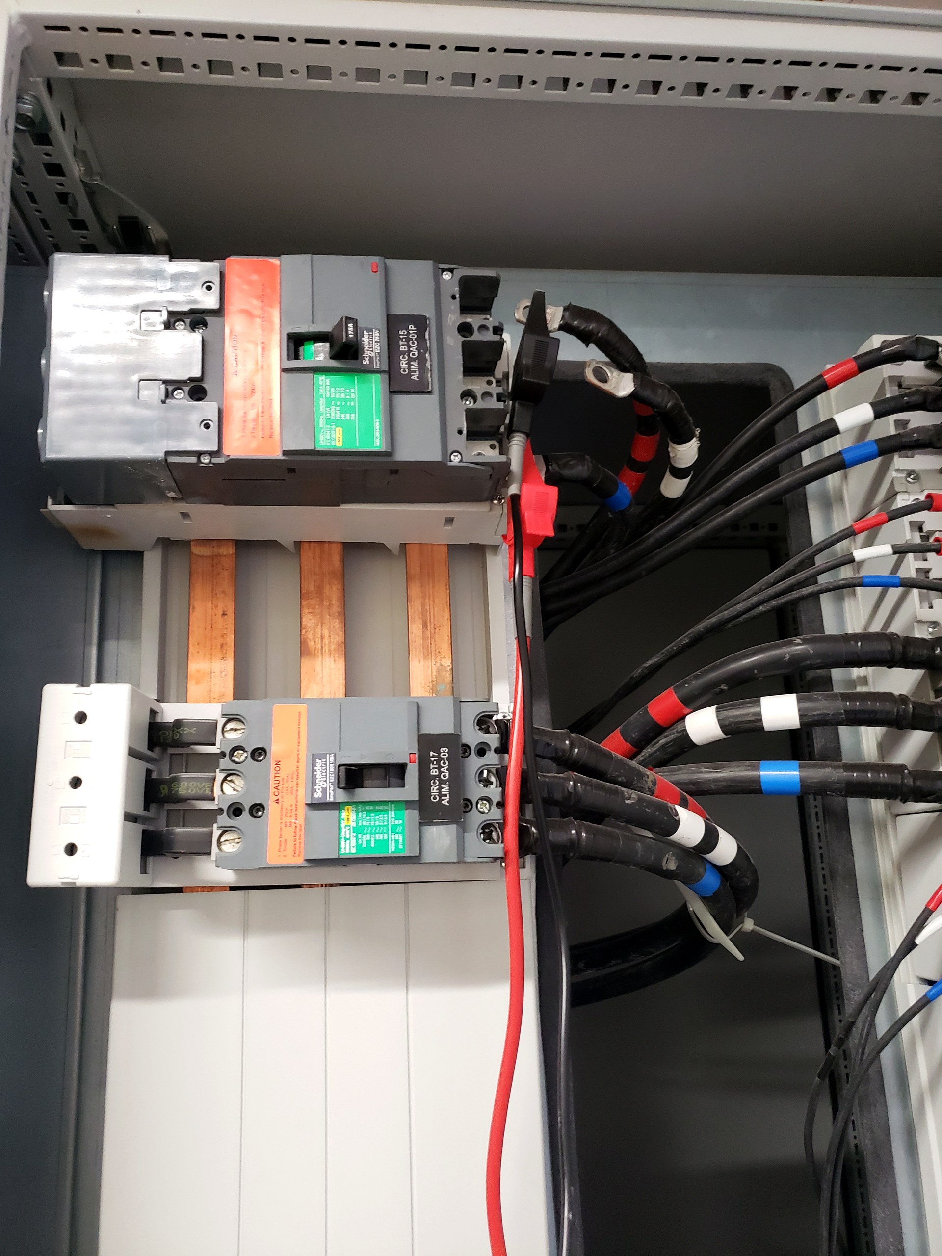 Detalhe interno de quadro elétrico com barramento de cobre e disjuntores em caixa moldada, instalação inspecionada pela Token Engenharia