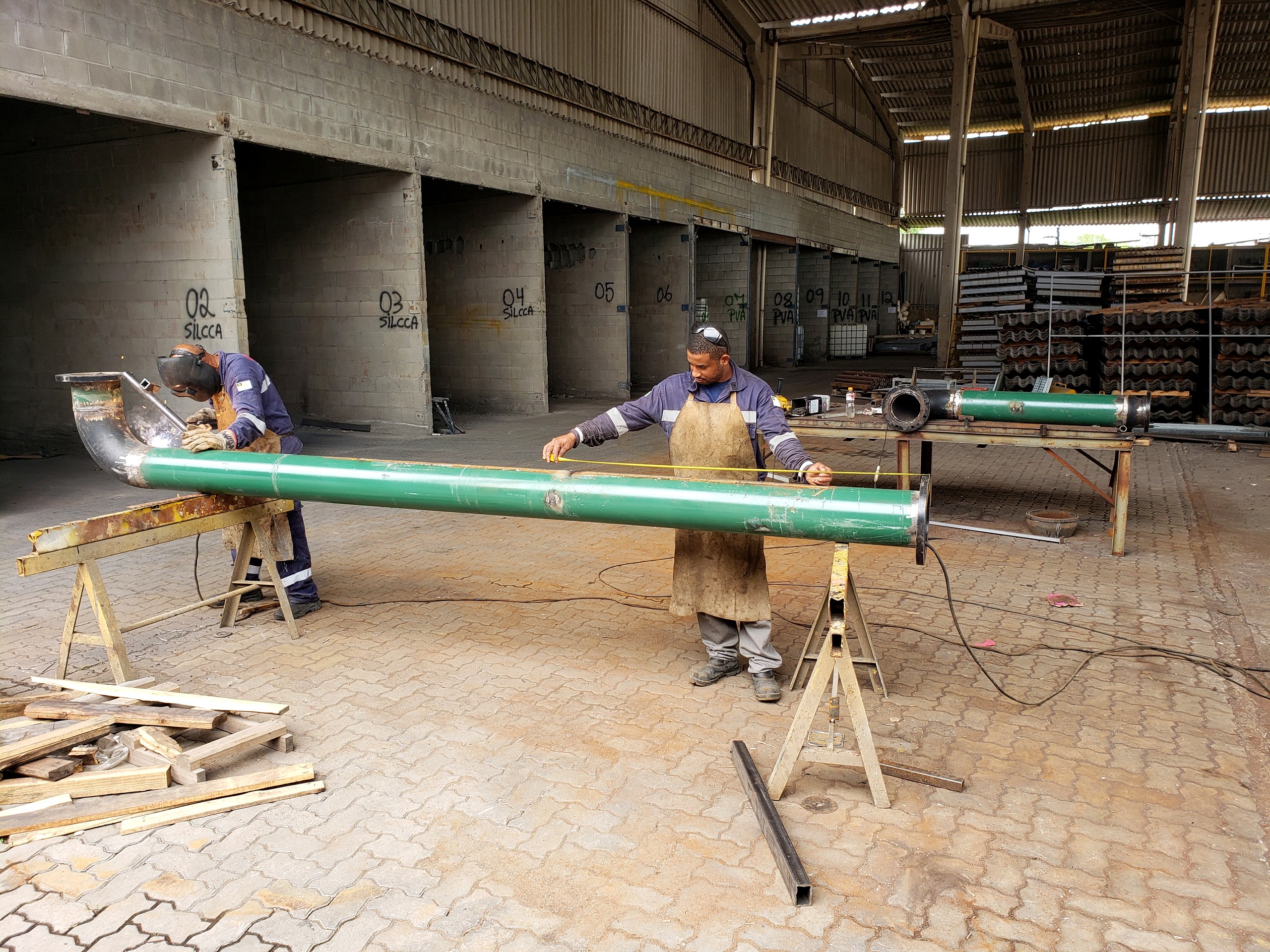 Caldeireiros na fabricação de tubulação de grande diâmetro em galpão de caldeiraria