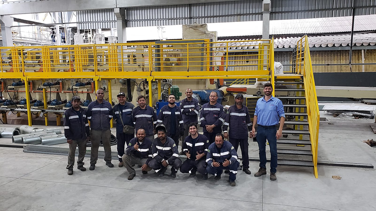 Equipe da Token Engenharia na fábrica, entre a linha industrial montada e o mezanino
