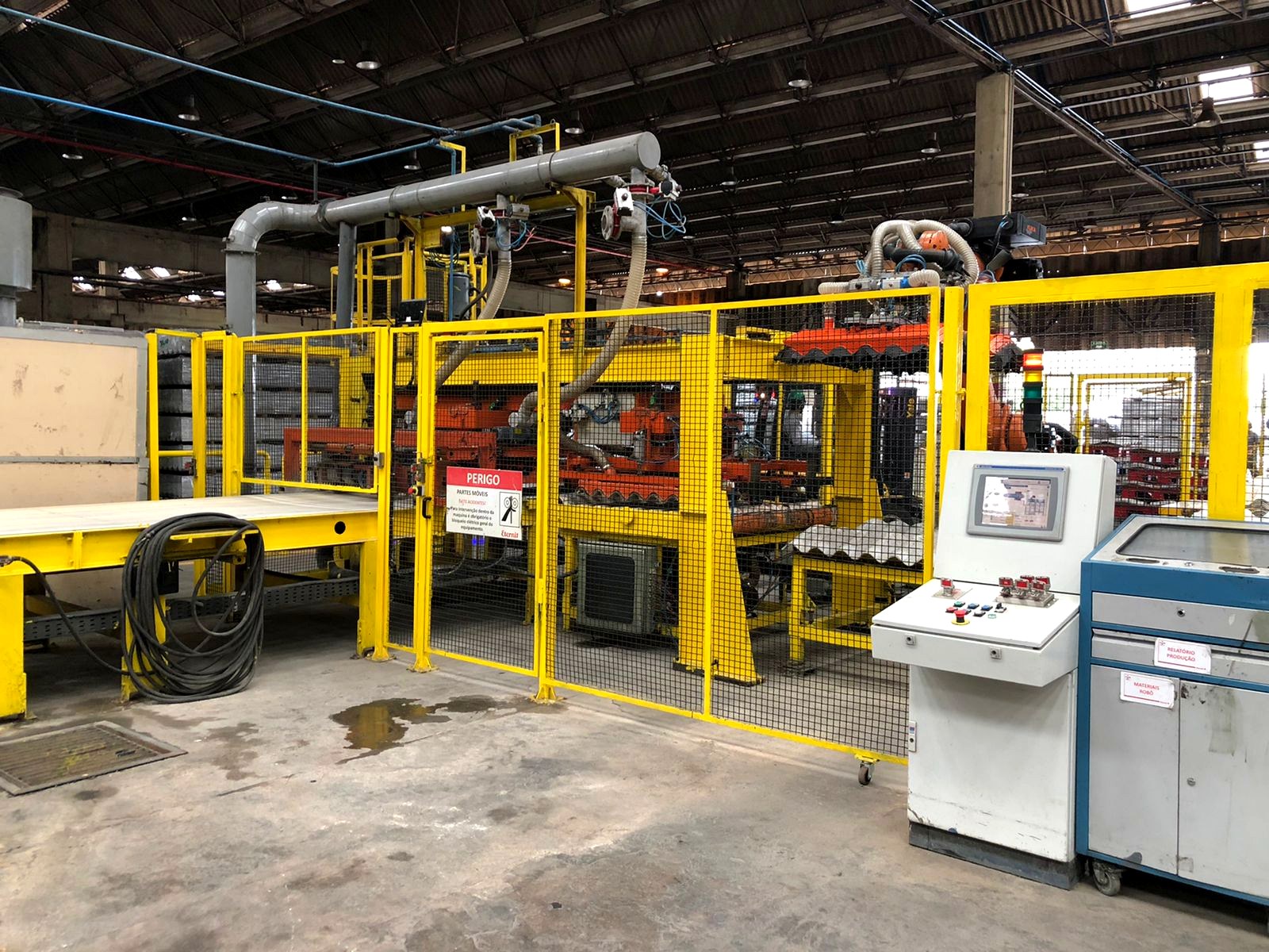 Painel de comando elétrico com IHM ao lado de linha automatizada industrial, fabricado pela Token Engenharia