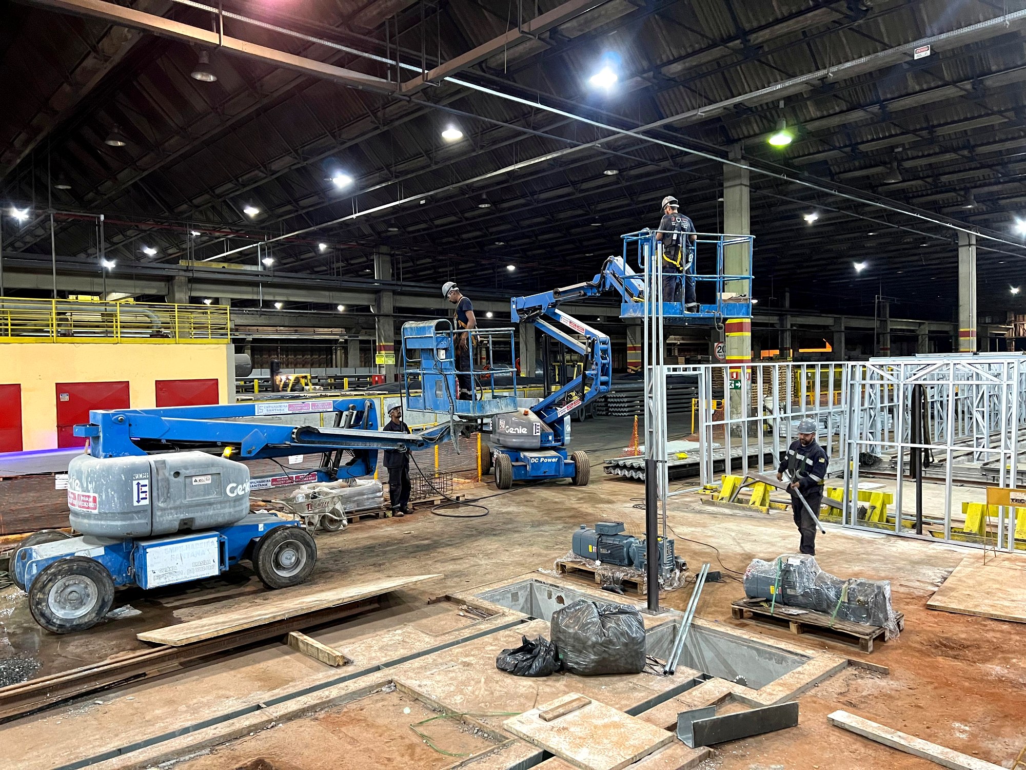 Plataformas elevatórias e equipe da Token em montagem de estrutura dentro de planta industrial
