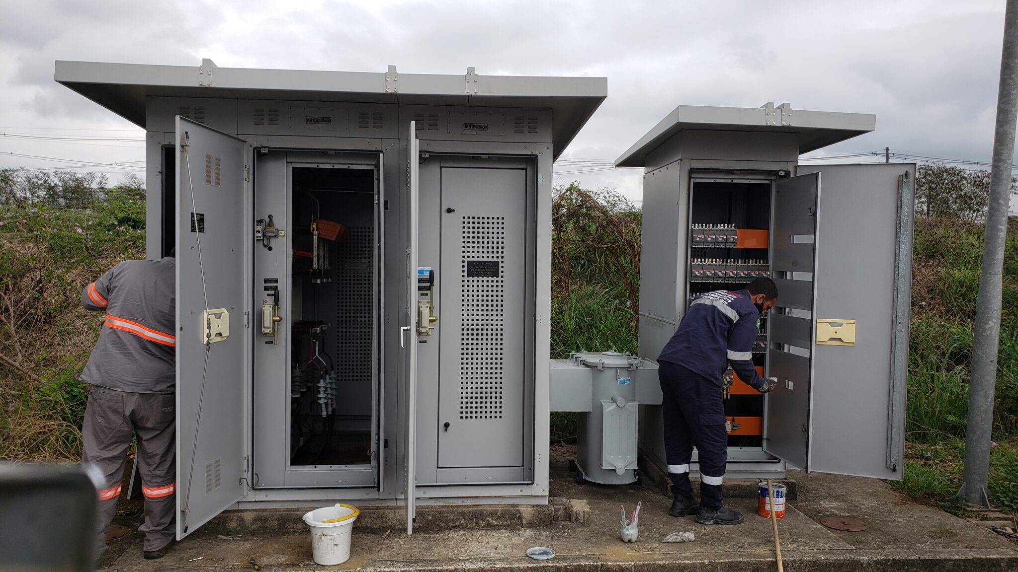 Engenheiros da Token Engenharia com EPI inspecionando painéis e cabines elétricas em campo para emitir o laudo de conformidade elétrica