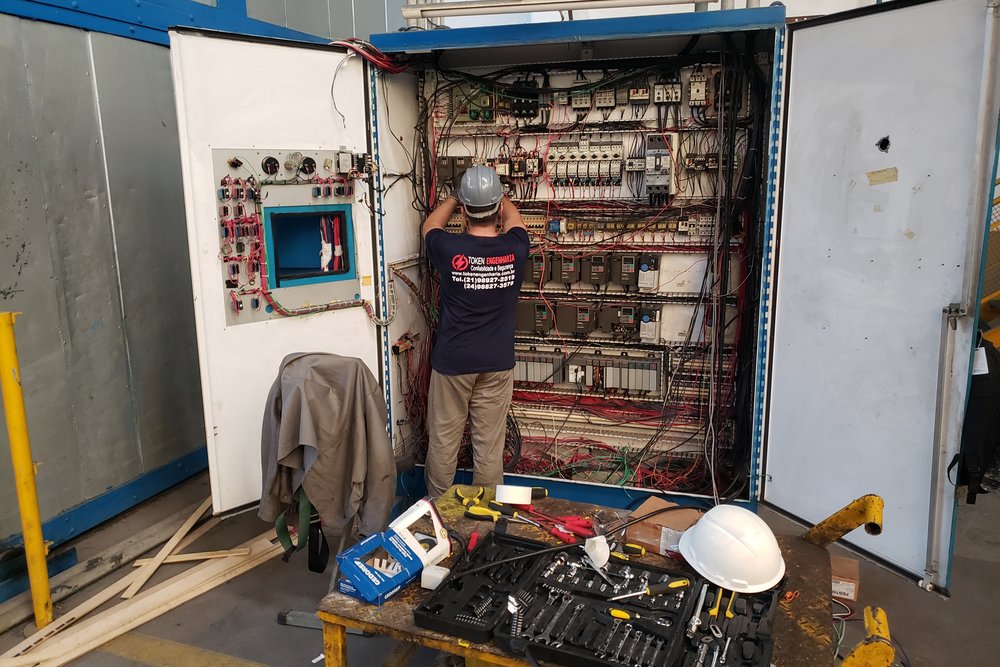 Técnico da Token em manutenção de painel de comando elétrico industrial aberto