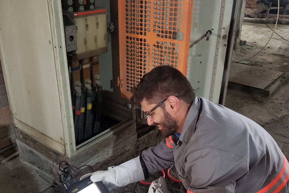 Engenheiro da Token medindo parâmetros elétricos com analisador em quadro de subestação