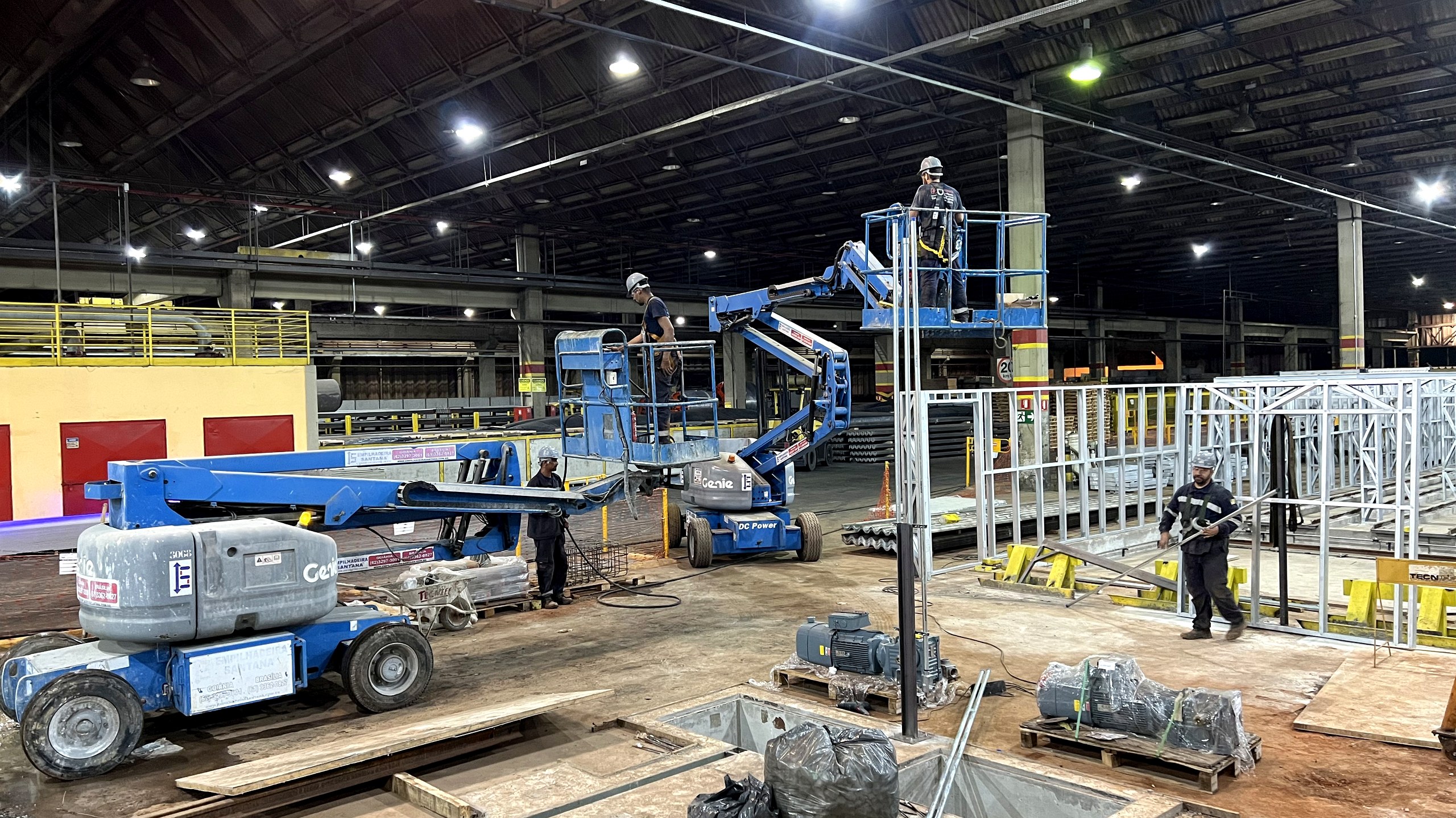 Equipe da Token Engenharia em montagem elétrica industrial dentro de galpão, com plataformas elevatórias