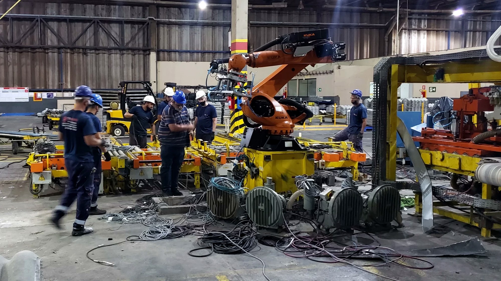 Equipe realizando montagem eletromecânica em planta industrial com motores e painéis elétricos