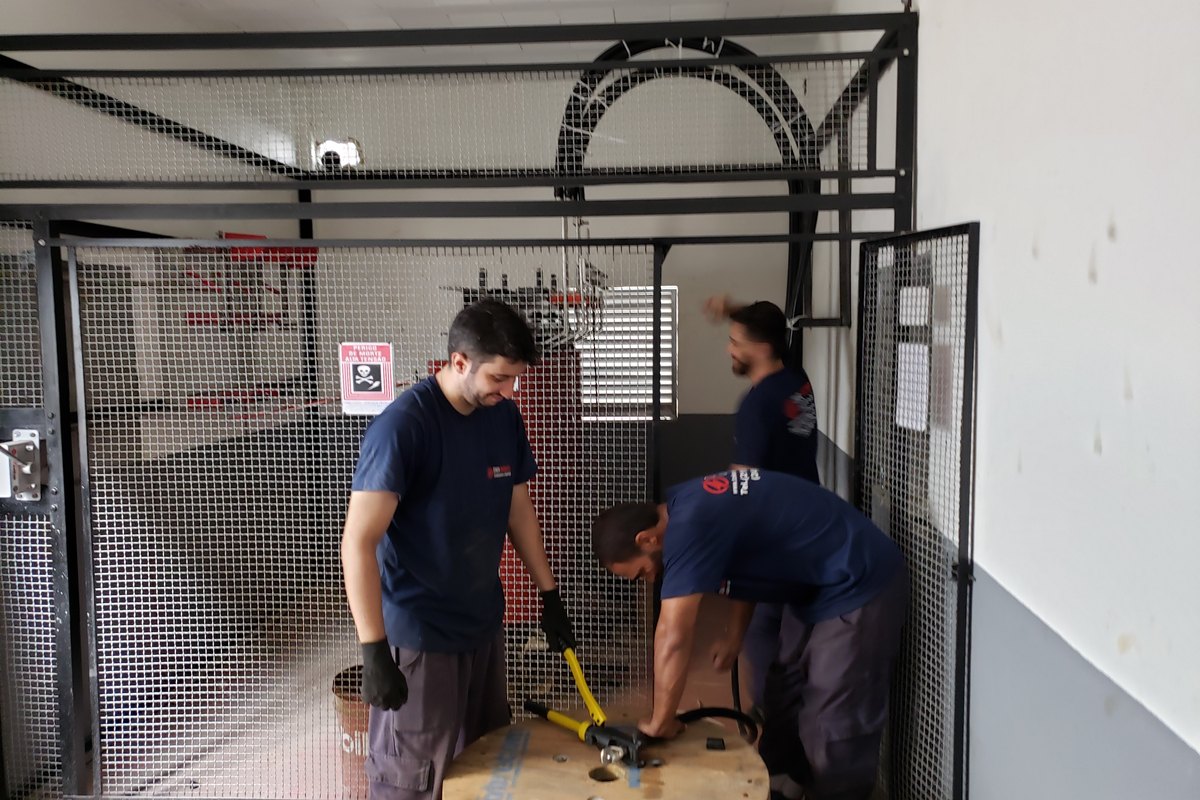 Equipe crimpando terminais de cabo com prensa hidráulica em subestação