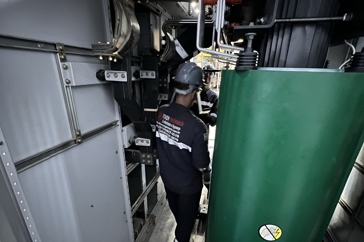 Técnico junto a transformador a seco em cubículo de subestação de média tensão