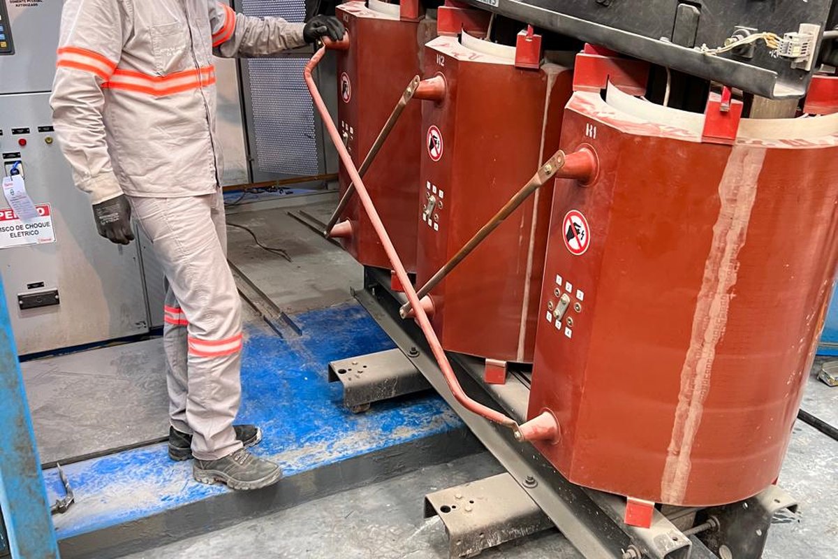 Técnico posiciona transformador a seco de média tensão na montagem de subestação