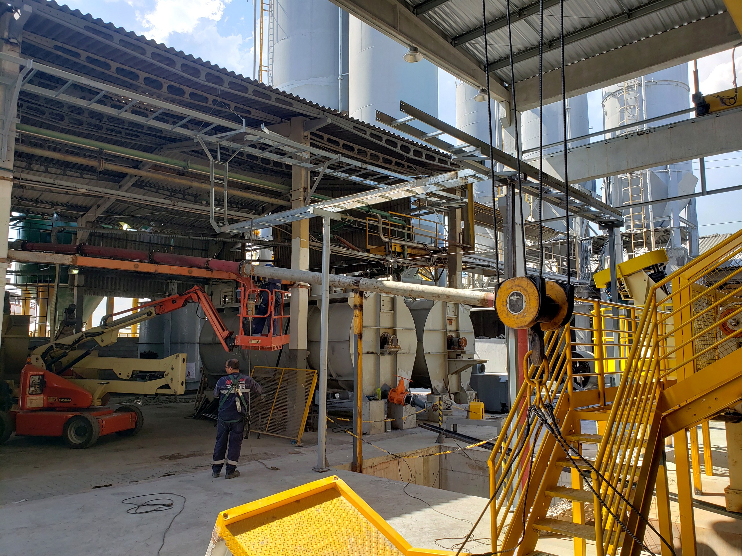 Montagem de tubulação industrial aérea em planta de processo com silos e estruturas