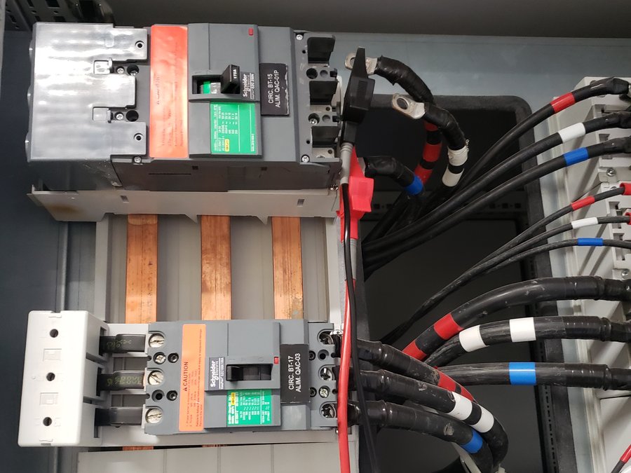 Detalhe interno de quadro elétrico com disjuntores e barramento de cobre