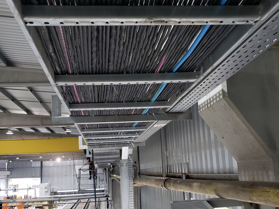 Leitos de eletrocalha com cabeamento de potência organizado em planta industrial