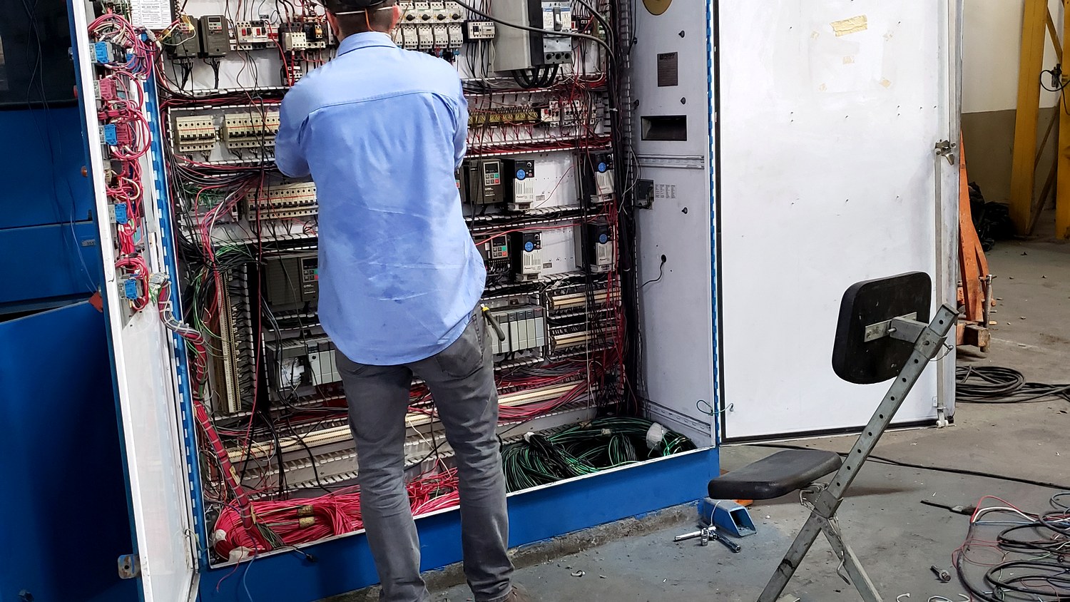 Engenheiro da Token Engenharia trabalhando no interior de um quadro de comando elétrico industrial aberto