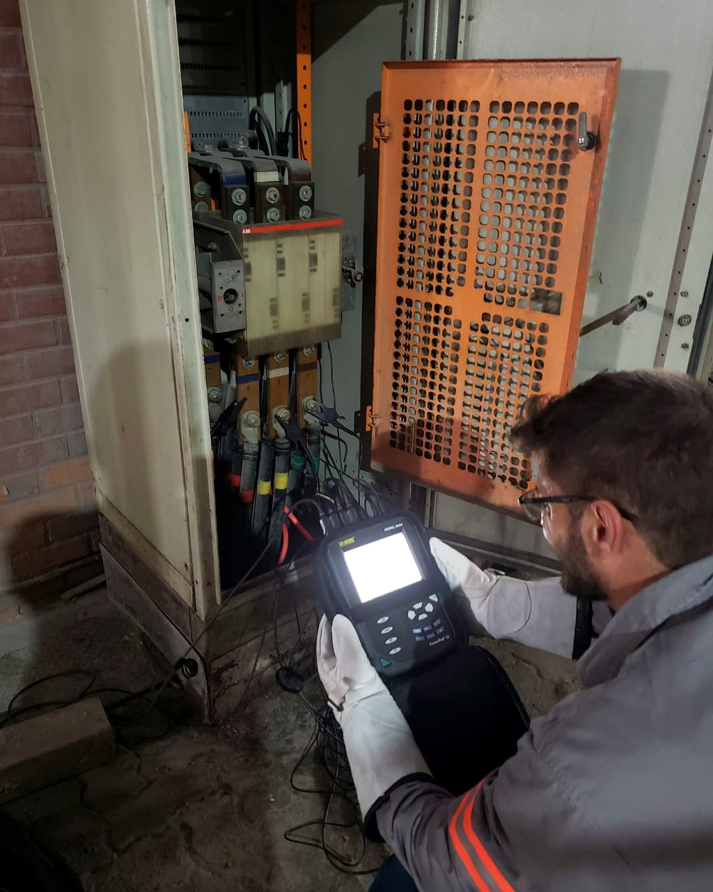 Técnico da Token medindo qualidade de energia com analisador conectado ao barramento de um painel elétrico industrial para o RISE