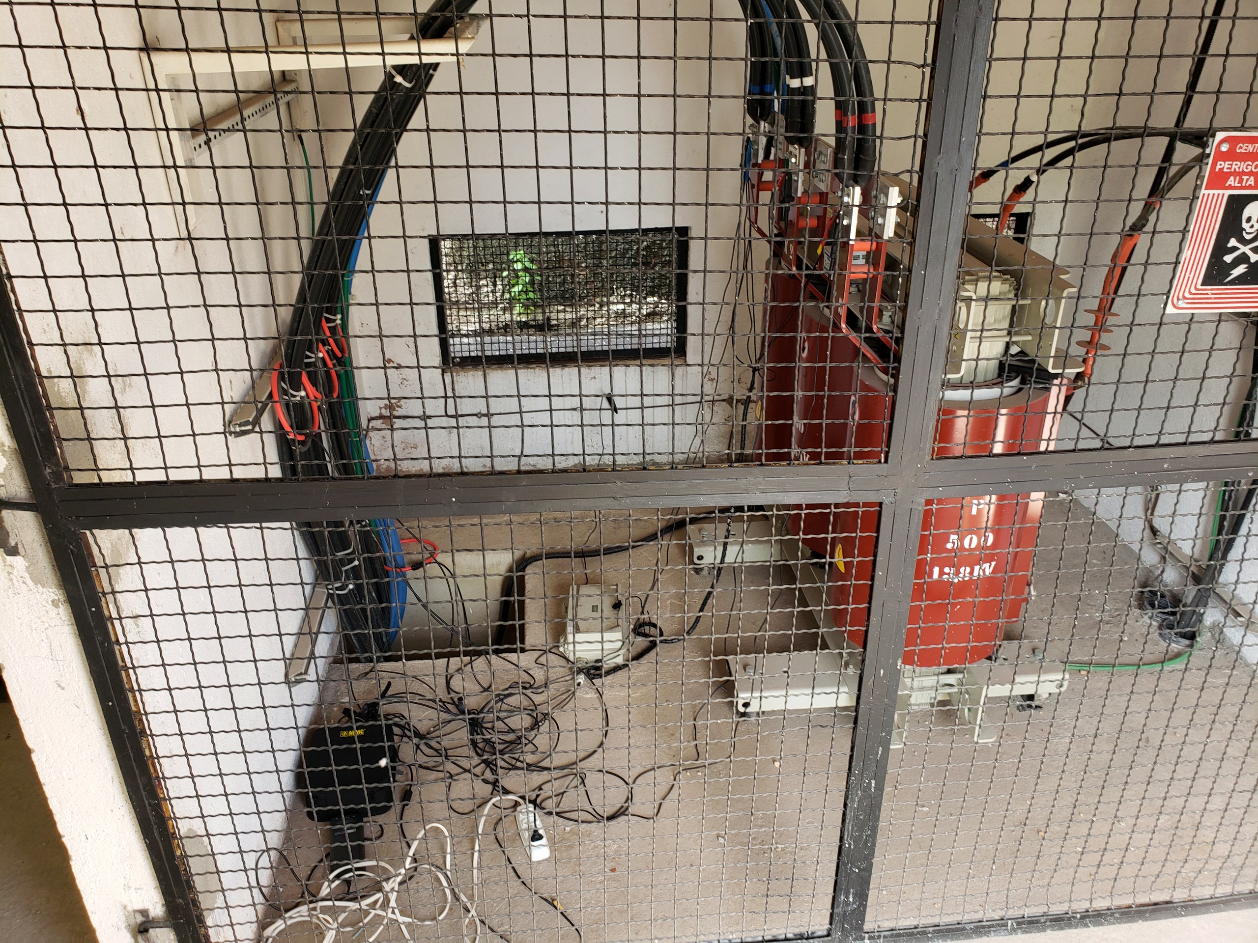 Transformador a seco em cabine de subestação de energia atrás de grade de proteção, instalação inspecionada pela Token Engenharia