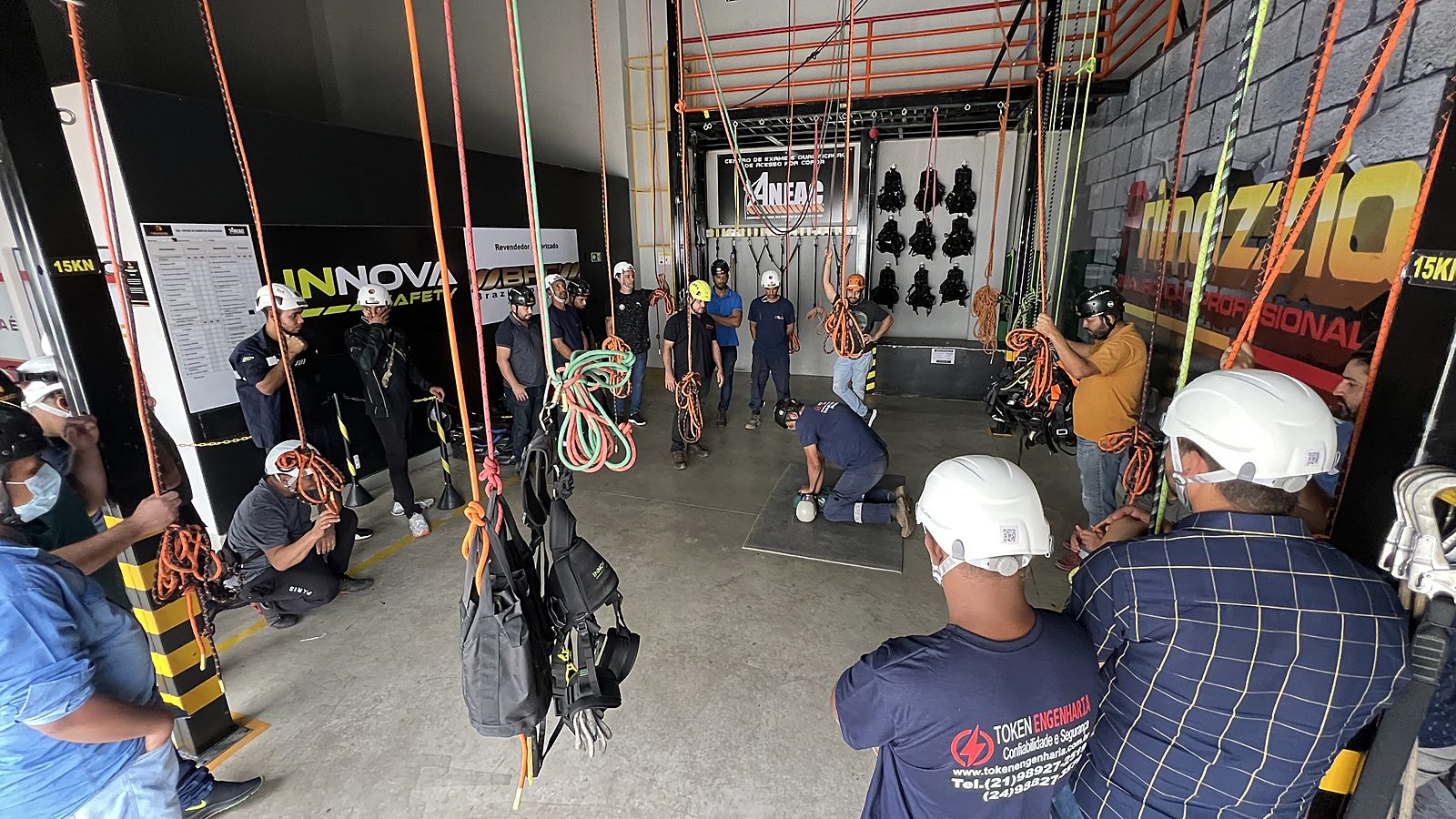Treinamento de resgate em altura em andamento, com técnicos manuseando cordas e equipamentos de salvamento