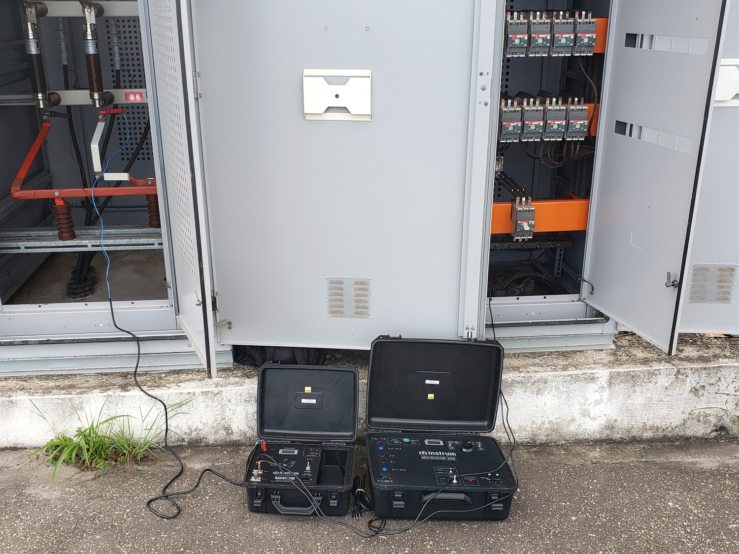 Maletas de instrumentos de ensaio ligadas a cubículo de média tensão e quadro de baixa tensão abertos, durante inspeção elétrica em campo da Token para laudo elétrico